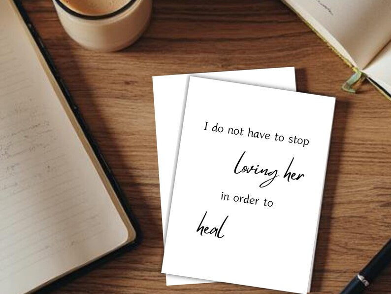 Two cards reading I do not have to stop loving her in order to heal with a notebook and coffee